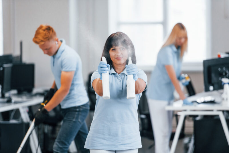 Group of workers clean modern office together at daytime
